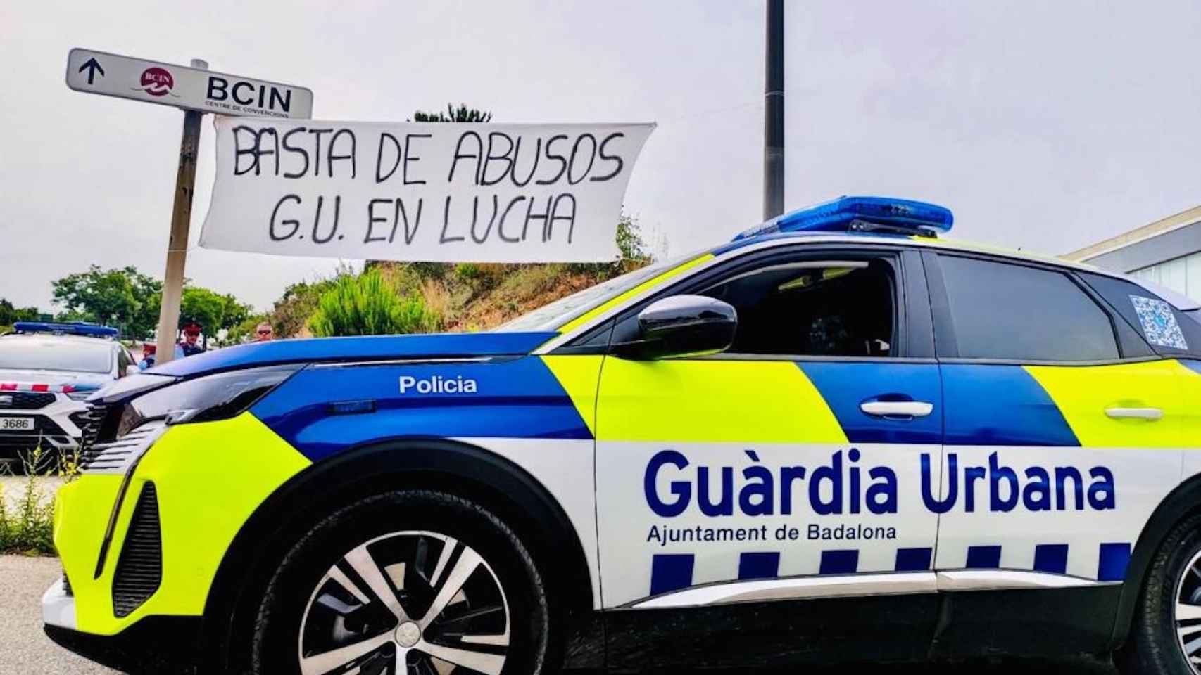 La pancarta de la manifestación con un coche de la Guardia Urbana al frente / CEDIDA