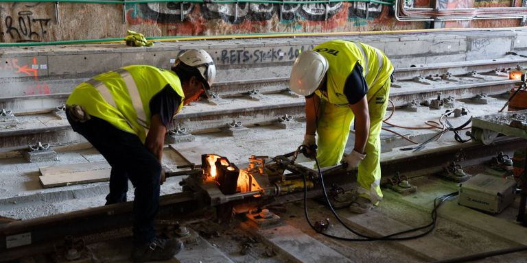 Dos obreros ensamblan dos partes de las nuevas vías ferroviarias / LUIS MIGUEL AÑÓN - METRÓPOLI