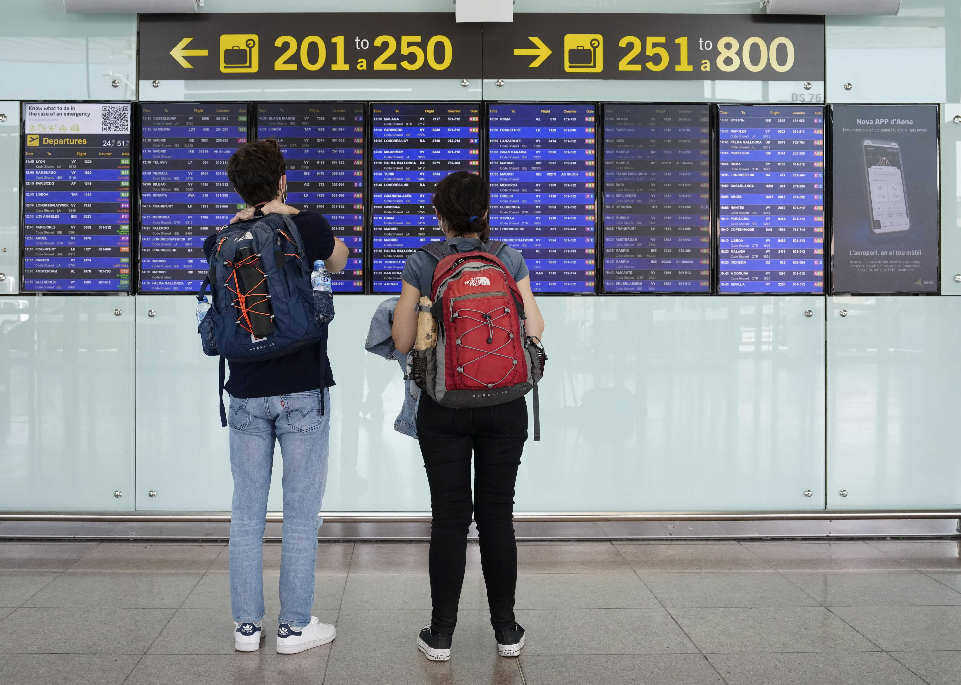 Dos viajeros consultan los paneles con los vuelos programados en el aeropuerto de El Prat, en Barcelona