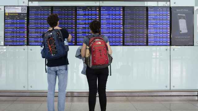 Dos viajeros consultan los paneles con los vuelos programados en el aeropuerto de El Prat, en Barcelona