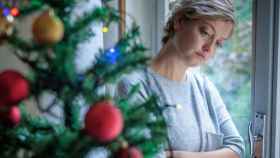 Una mujer pensativa junto a un árbol de Navidad / QUIRÓNSALUD
