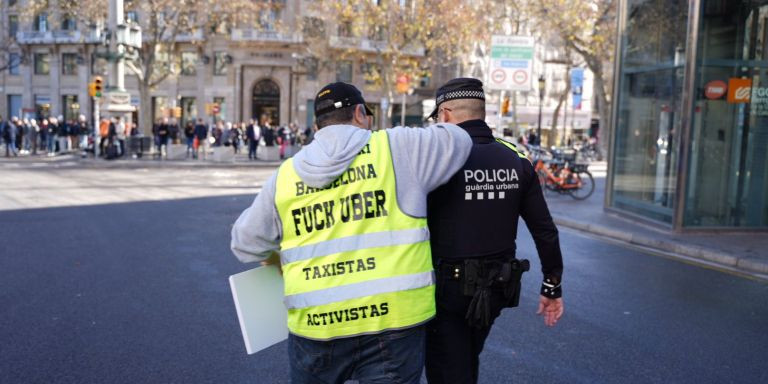 Un taxista junto a un guardia urbano en la protesta en Barcelona / LUIS MIGUEL AÑÓN