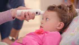 Una madre pone el termómetro a una niña para comprobar si tiene fiebre / PEXELS