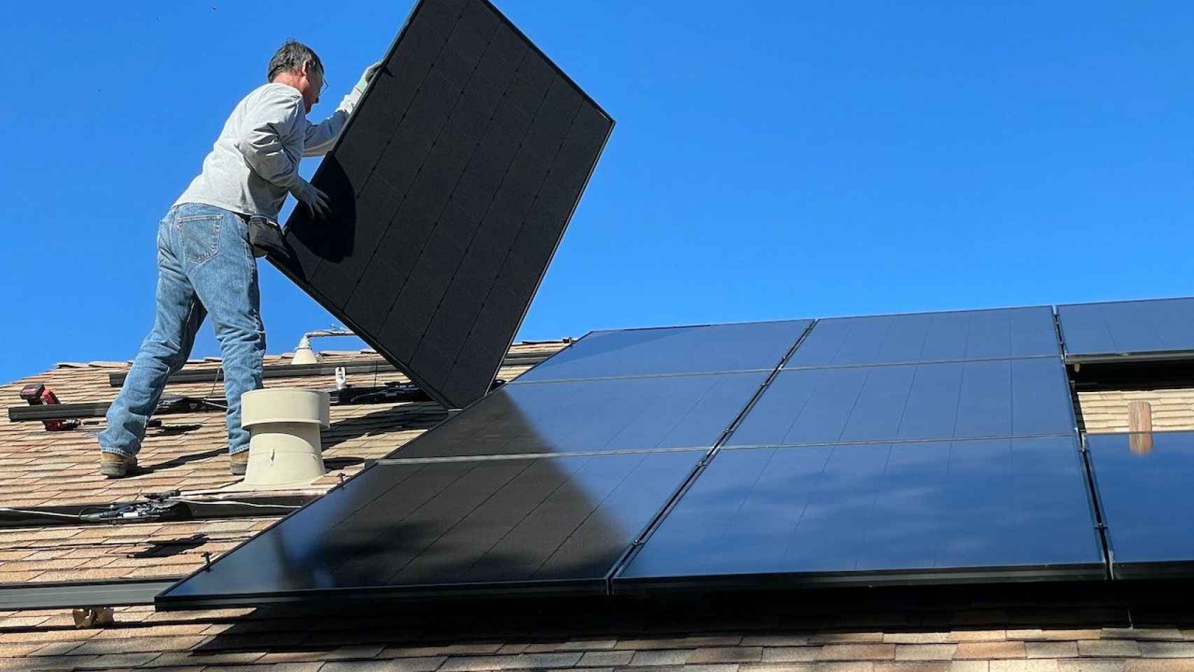 Un hombre instalando paneles fotovoltaicos en un tejado