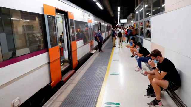 Varios pasajeros esperan ante un tren parado en la estación de Barcelona-Sants