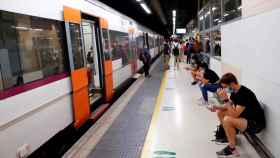 Varios pasajeros esperan ante un tren parado en la estación de Barcelona-Sants