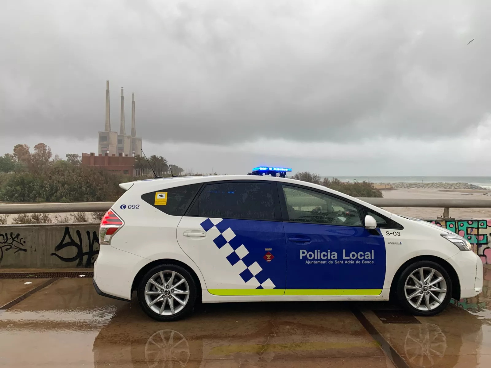 Un coche de la Policía Local de Sant Adrià con las Tres Chimenea de fondo / ARCHIVO