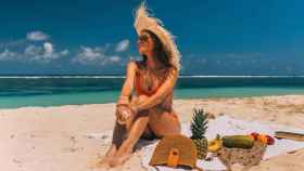 Una mujer toma el sol feliz en la playa / PEXELS