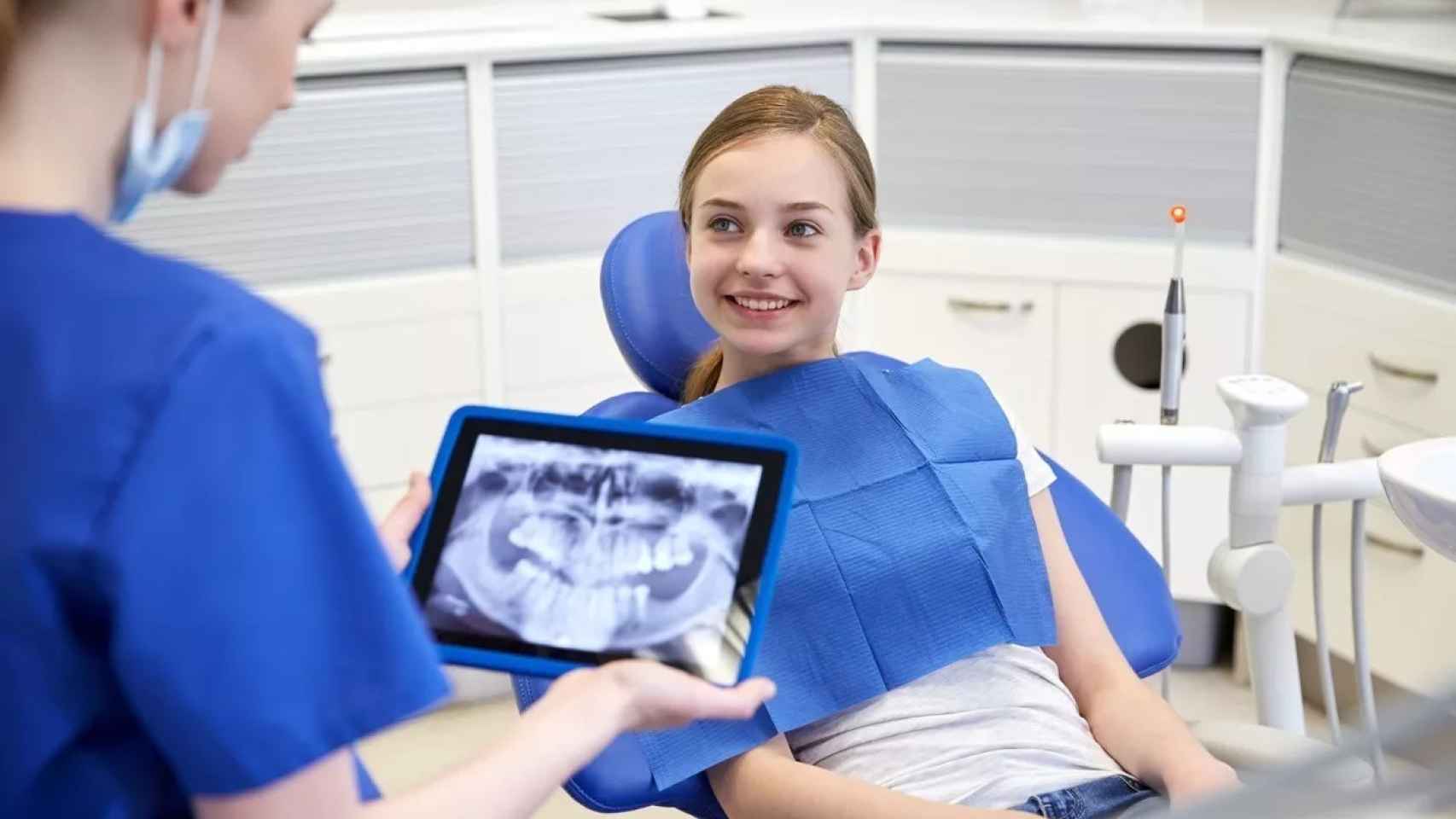 Una odontóloga observa una radiografía dental de una adolescente / EP