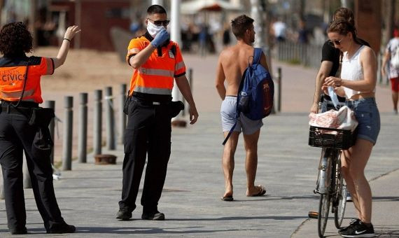 Agentes cívicos de Barcelona informan a una joven de la obligatoriedad de llevar mascarilla / EFE - TONI ALBIR