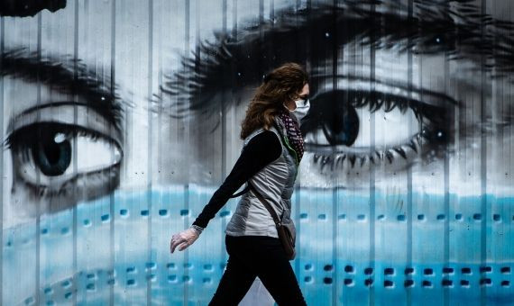 Una mujer camina ante un grafiti en Barcelona este martes / EFE - ENRIC FONTCUBERTA